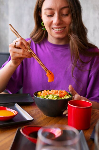 Mujer comiendo plato de salmón en el restaurante