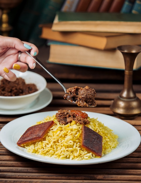 Mujer comiendo plov govurma tradicional con una cuchara.