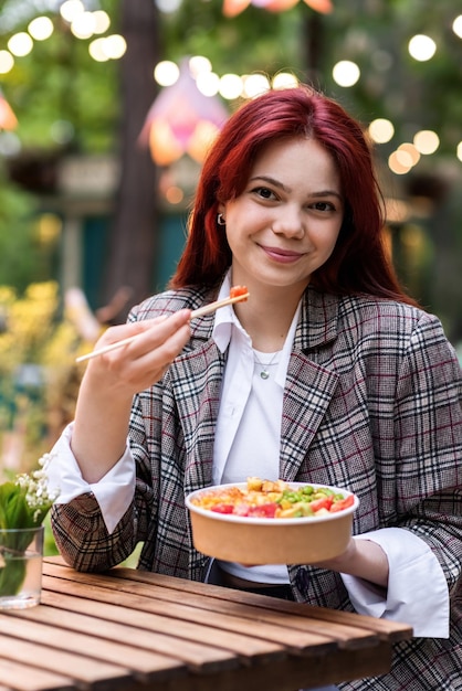 Foto gratuita una mujer comiendo un poke en un parque