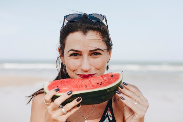 Mujer comiendo sandía en la playa