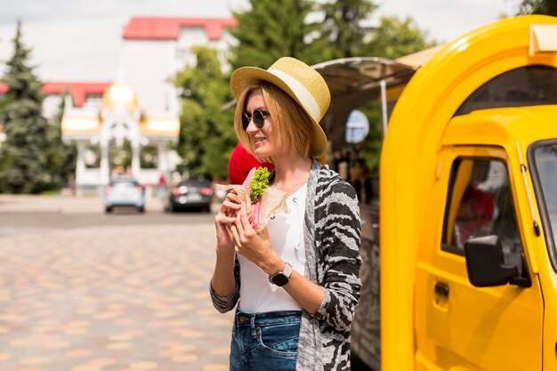 Mujer comiendo un sándwich y mirando a otro lado