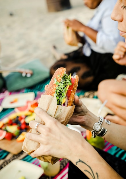 Mujer comiendo un sandwich en la playa