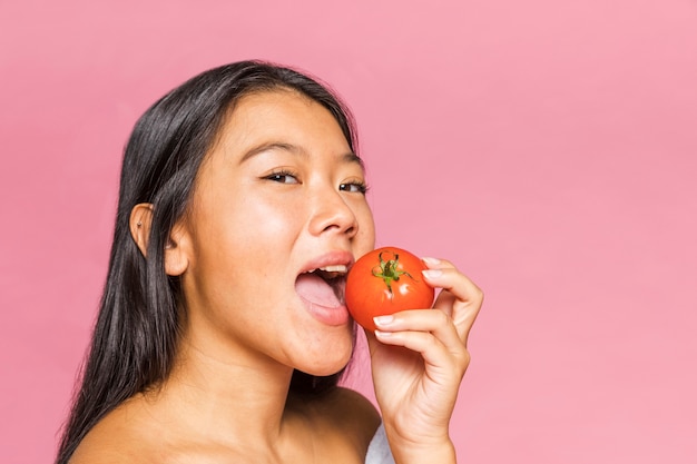 Mujer comiendo un tomate adulto