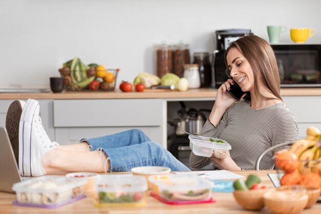 Mujer comiendo y trabajando en la cocina