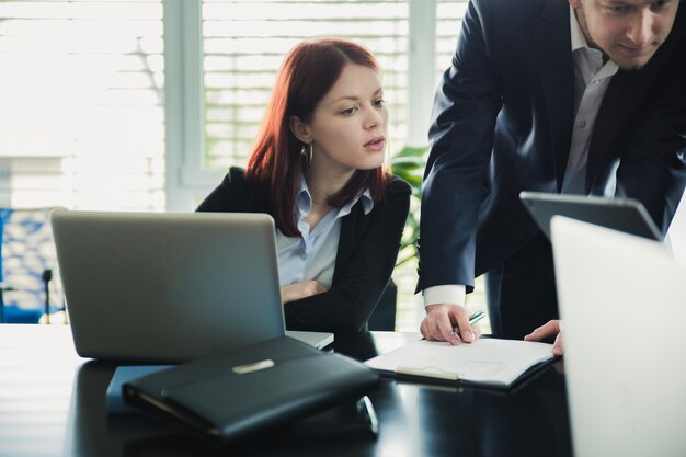 Mujer con compañero de trabajo viendo la computadora portátil