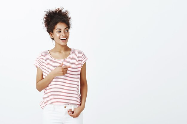 Mujer complacida con peinado afro posando en el estudio