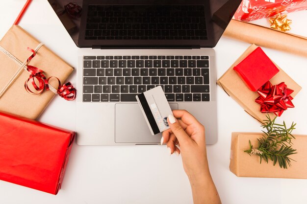 Mujer comprando regalos de Navidad en línea con regalos en la mesa