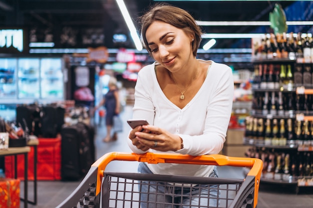 Mujer de compras en el supermercado y hablando por teléfono