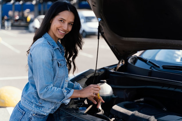 Foto gratuita mujer comprobando el aceite de su coche