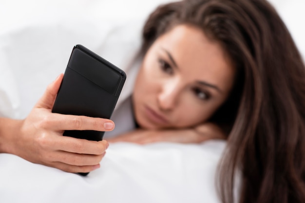 Foto gratuita mujer comprobando su teléfono después de despertar primer plano