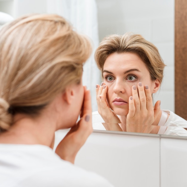 Mujer comprobando sus ojos en el espejo