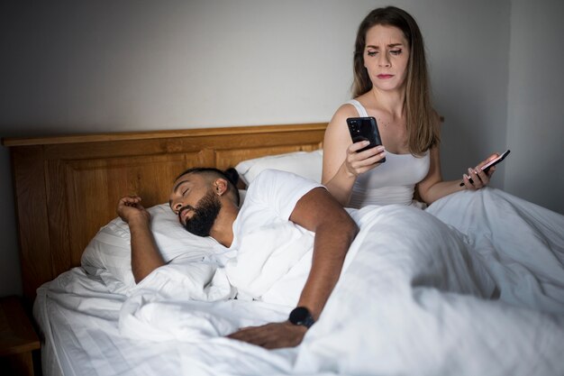 Mujer comprobando el teléfono de su novio mientras duerme