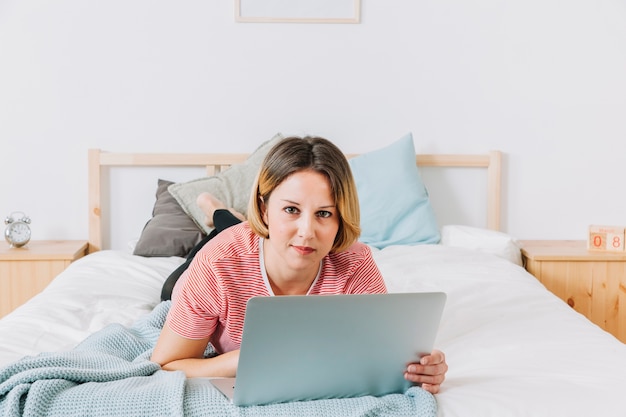 Mujer con la computadora portátil que mira la cámara