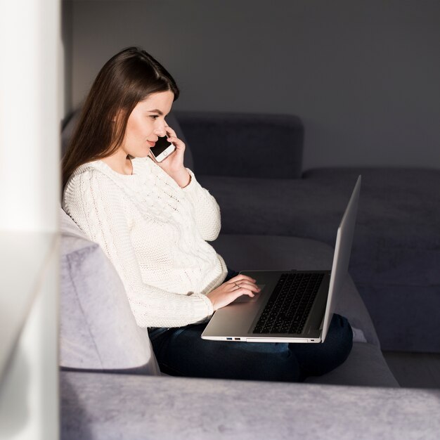 Mujer con computadora portátil y teléfono inteligente