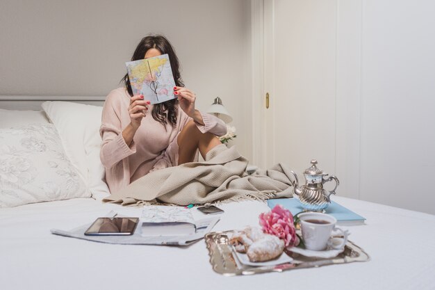 Mujer concentrada comprobando un mapa en su habitación