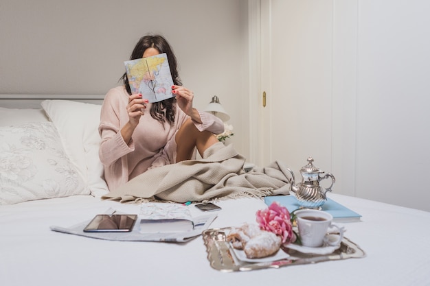 Mujer concentrada comprobando un mapa en su habitación