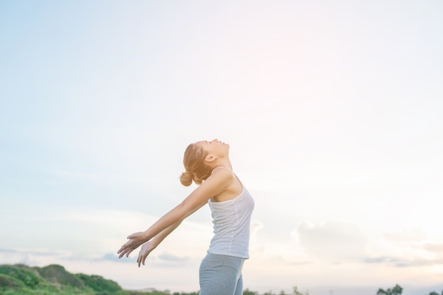 Mujer concentrada estirando sus brazos con el cielo de fondo