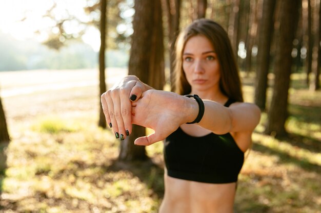 Mujer concentrada joven que hace los ejercicios para los brazos, calentándose antes de correr