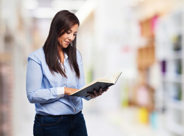 Mujer concentrada leyendo un libro con fondo borroso