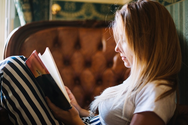 Mujer concentrada con libro en casa