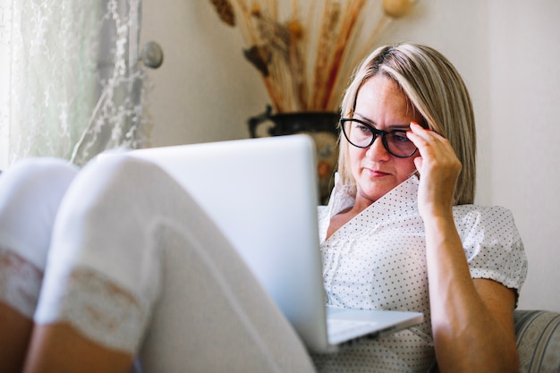 Foto gratuita mujer concentrada que trabaja con la computadora portátil en casa