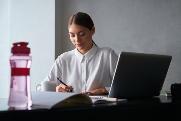 Mujer concentrada trabajando en la computadora portátil mientras se queda en casa