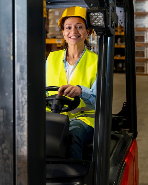 Foto gratuita mujer conduciendo la máquina de carga de almacén