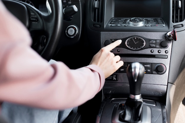 Mujer conductora ajustando la configuración de su automóvil