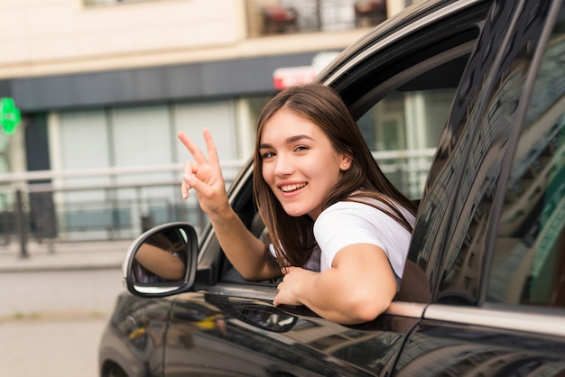 Foto gratuita mujer conductora de coche saluda como señal de despedida en la calle