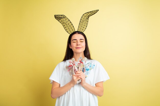 Mujer de conejito de Pascua con emociones brillantes en pared amarilla