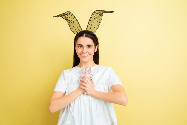 Mujer de conejito de Pascua con emociones brillantes en pared amarilla