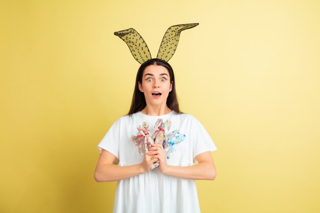 Mujer de conejito de Pascua con emociones brillantes en pared amarilla