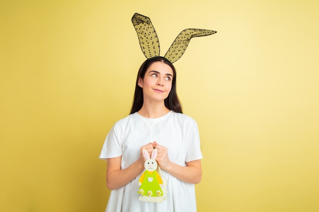 Foto gratuita mujer de conejito de pascua con emociones brillantes en pared amarilla