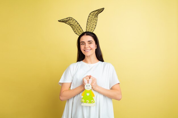 Mujer de conejito de Pascua con emociones brillantes en pared amarilla