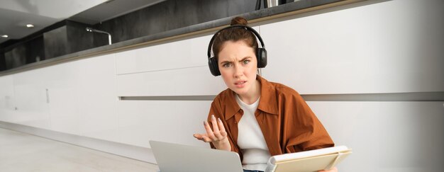 Foto gratuita mujer confundida y frustrada con auriculares estudiante no entiende algo mientras hace la tarea