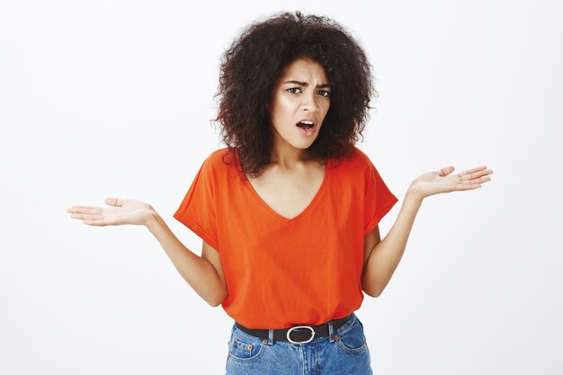 Mujer confundida con peinado afro posando en el estudio