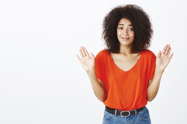 Mujer confundida con peinado afro posando en el estudio