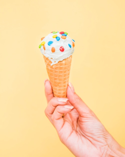 La mujer con el cono fresco de la galleta del helado con asperja