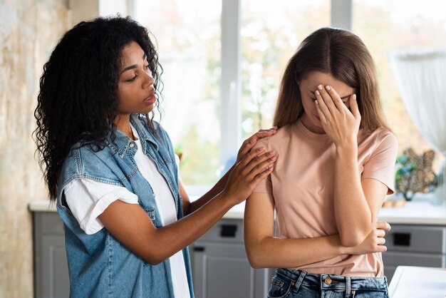 Mujer consolando a su amiga preocupada en la cocina