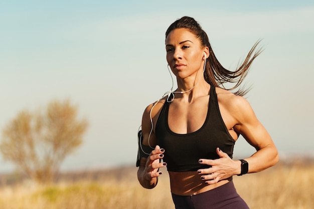 Mujer de construcción muscular motivada trotando mientras entrena deportes en la naturaleza Espacio de copia
