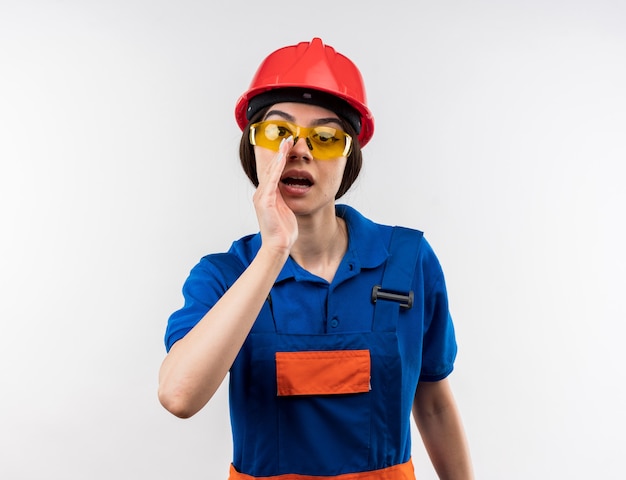 Mujer constructora joven sospechosa en uniforme con gafas llamando a alguien