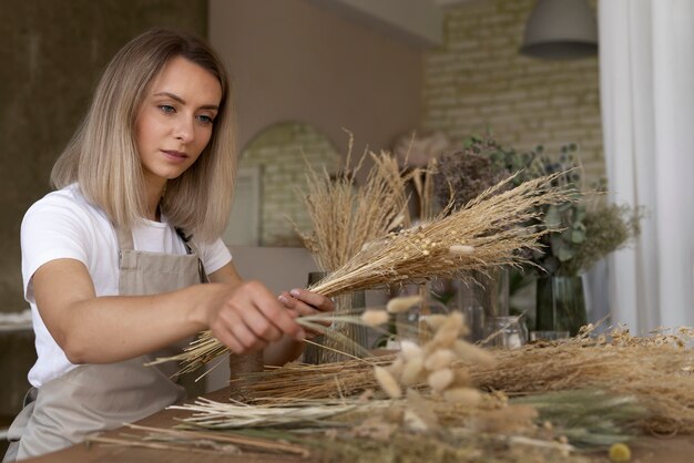 Mujer construyendo su propio arreglo de flores secas