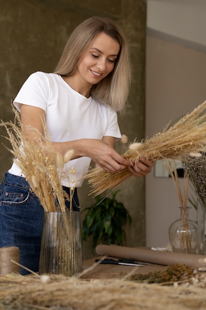 Mujer construyendo su propio arreglo de flores secas