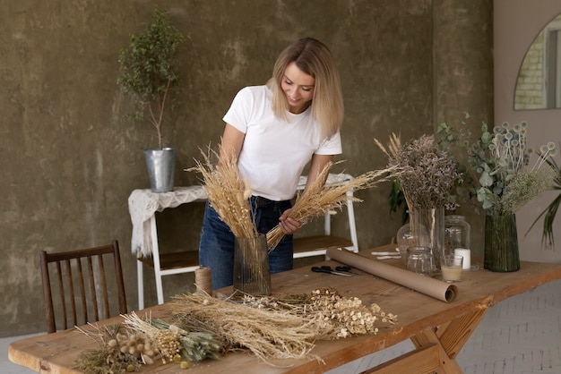 Mujer construyendo su propio arreglo de flores secas