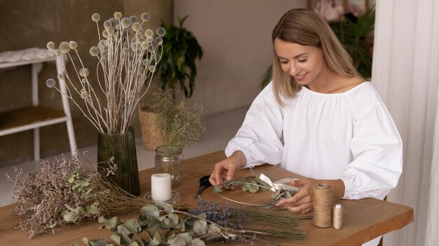 Mujer construyendo su propio arreglo de flores secas
