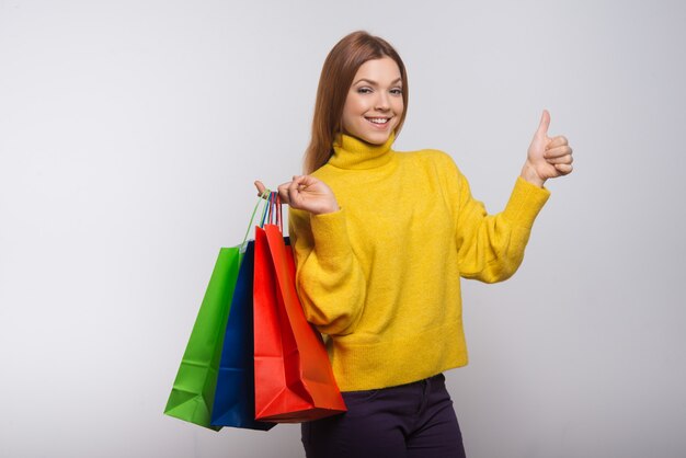 Mujer contenta con bolsas de compras mostrando el pulgar