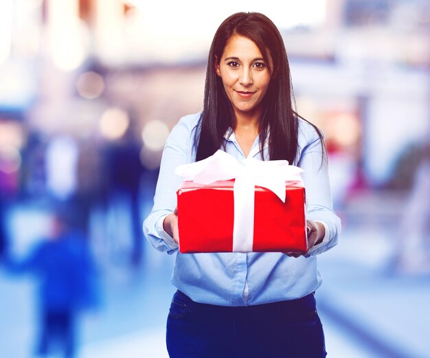 Mujer contenta ofreciendo un regalo con un lazo blanco