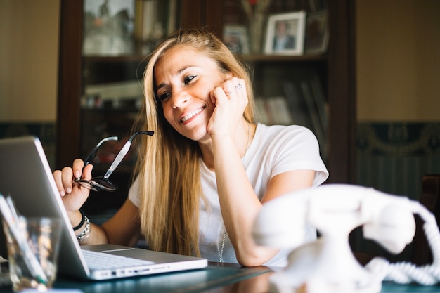 Foto gratuita mujer contenta que mira la computadora portátil mientras que charla