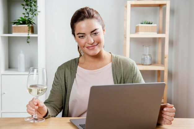 Mujer con copa de vino usando laptop