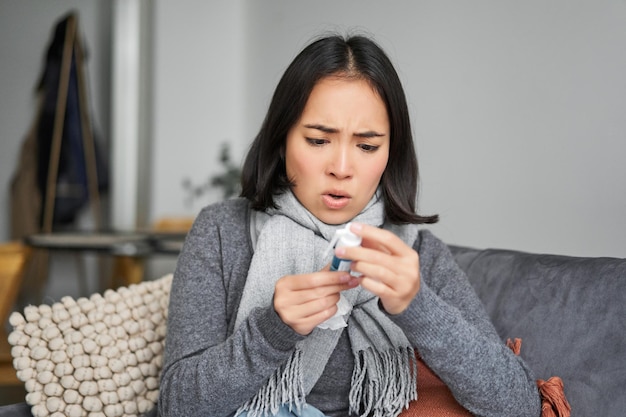 Mujer coreana enferma mirando el termómetro con cara preocupada resfriándose con fiebre con covid